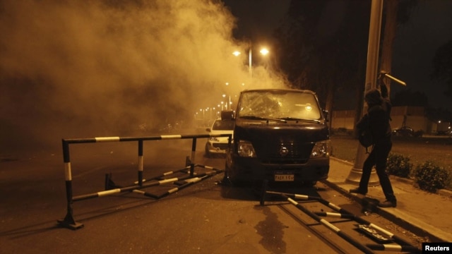 An anti-Muhammad Morsi protester damages a riot-police vehicle during a demonstration in front of the presidential palace in Cairo on December 4.