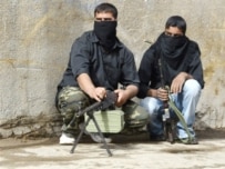 Shi'ite fighters take a combat position on a street in Baghdad's Al-Sadr City (AFP)