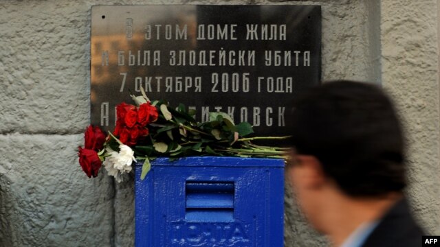A man walks past a marble plaque on the apartment building where journalist and rights activist Anna Politkovskaya was killed in 2006. 