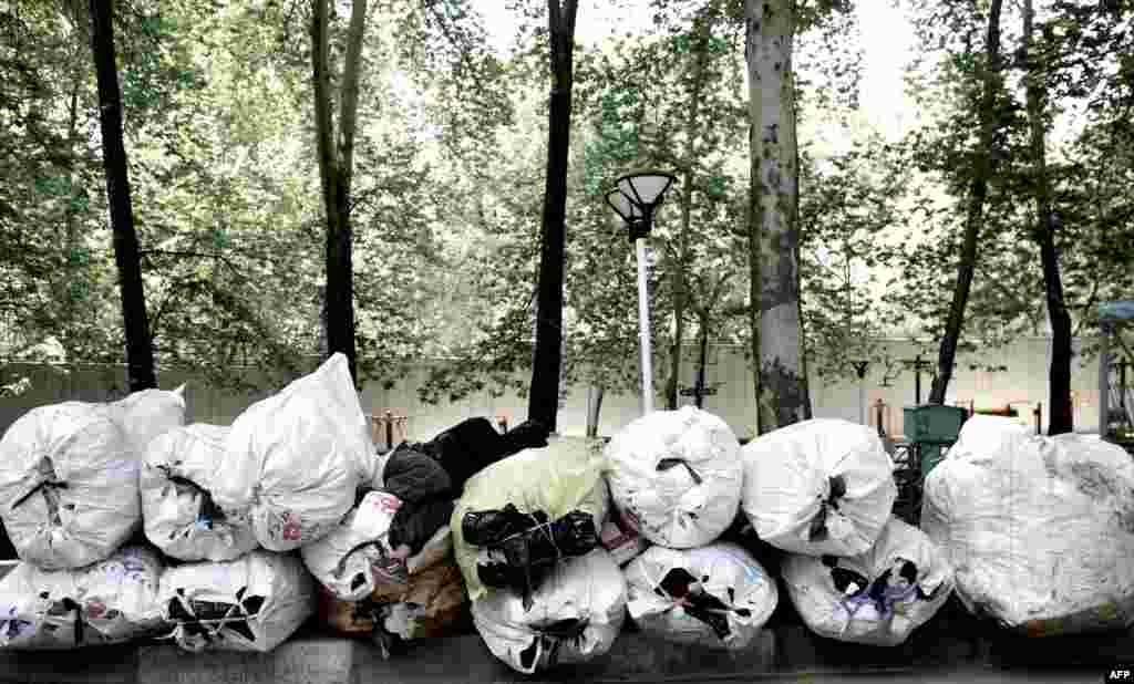 A scavenger sleeps on a pile of items collected from trash bins as he waits for a vehicle to take them for recycling in northern Tehran. (AFP/Behrouz Mehri)