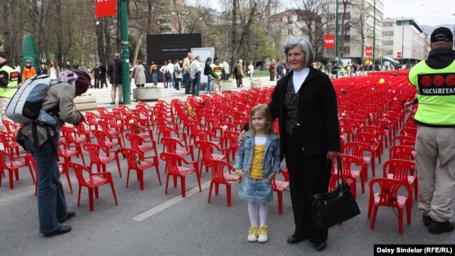 Biba Mehimovic stands with her granddaughter Sara in front of the small red chairs symbolizing the 643 children who died in the siege.