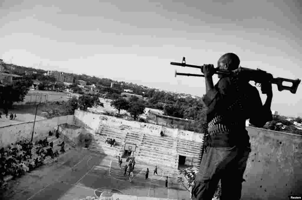 Jan Grarup of Denmark, a photographer working for the Laif Agency, won first prize in the Sports Features Stories category with the series "Women's Basketball, Mogadishu, Somalia." This picture shows an armed guard, paid by the Somali basketball association, watching over and protecting a women's basketball team as they play in Mogadishu.