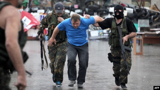 Members of the Vostok Battalion, a pro-Russia militia, escort an activist of the so-called People's Republic of Donetsk after detaining several of them following their storming of the regional state building in the eastern city of Donetsk on May 29.