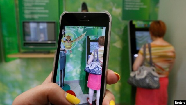 A Russian woman plays Pokemon Go while someone uses an ATM in Krasnoyarsk, Russia.
