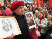 A Communist Party supporter holds portraits of Vladimir Lenin and Soviet dictator Joseph Stalin during a May Day celebration in Kyiv (AFP)