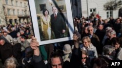Ұшақ апаты құрбандларын еске алу шарасы кезінде қайғылы оқиғада қаза тапқан Польша президенті Лех Качиньский мен оның зайыбының суретін ұстап тұрған адам. Варшава, 10 сәуір 2015 жыл.