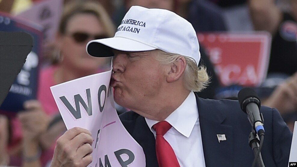 U.S. Republican presidential candidate Donald Trump kisses a "Women for Trump" placard during a rally at the Lakeland Linder Regional Airport in Lakeland, Florida, on October 12.