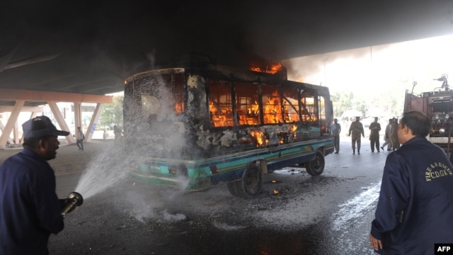 Firefighters extinguish a fire after protesters set alight a passenger bus in Karachi on March 27.