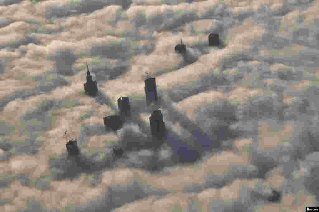 The tops of high-rise buildings stick out from a blanket of thick fog covering Warsaw early one morning. (Reuters/Mateusz Olszowy)