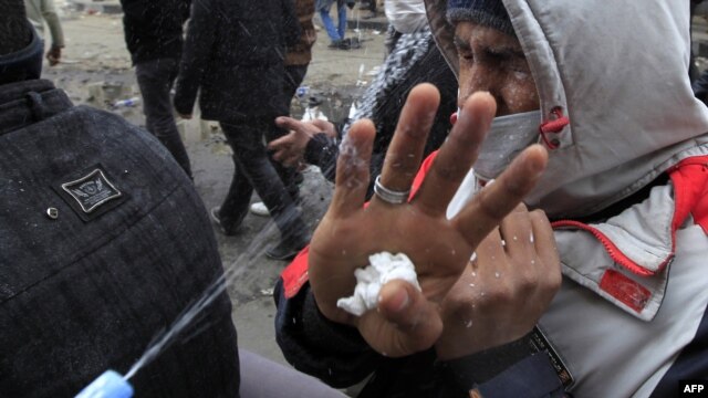 A protester splashes milk at the face of a fellow demonstrator to reduce the effects of tear gas fired by security forces during clashes near the Interior Ministry in Cairo on February 3.