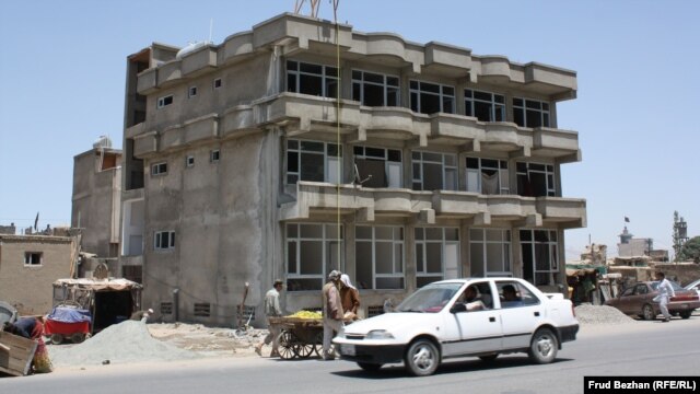 An apartment building stands unfinished on a street in Kabul