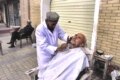 A man receives a shave from a street barber.