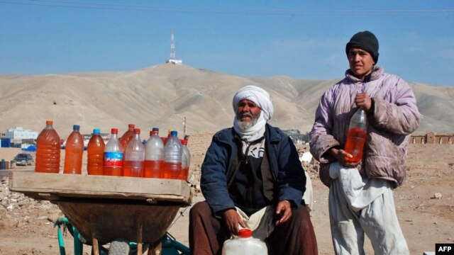 A man and his son sell fuel packed in water bottles on the outskirts of the Afghan city of Herat, near the western border with Iran, a result of the recent Iranian blockade.