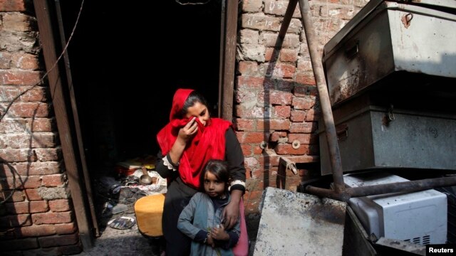 Anzila Semeul cries while sitting with her daughter in front of their home, after it was burnt by a mob on March 9, in Lahore on March 11.