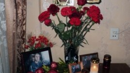 Flowers and photos of Uladzislau Kavalyou on a table in the apartment of his mother in Minsk