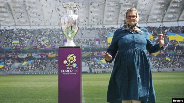 A Ukrainian woman poses for pictures next to the Euro 2012 trophy during a display to the public in central Kyiv on May 12.