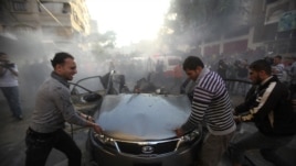 Palestinians try to remove the remains of a car after an Israeli air strike in Gaza City on November 14.