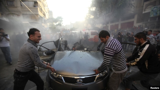 Palestinians try to remove the remains of a car after an Israeli air strike in Gaza City on November 14.