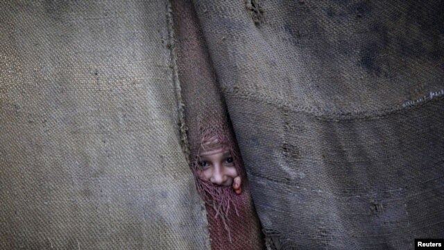 A Pashtun girl peeks through the doorway to her family dwelling in Peshawar.