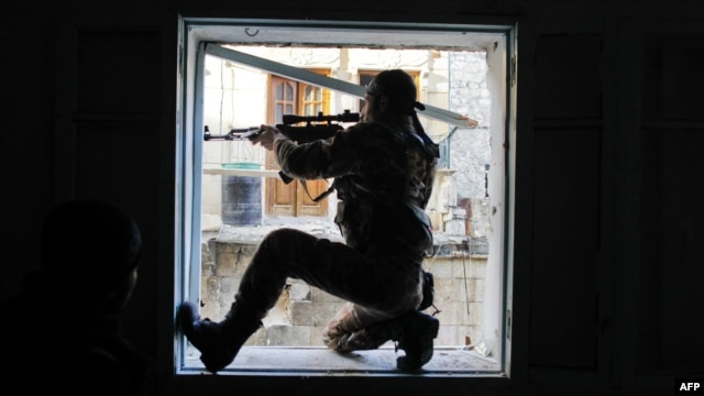 A member of Liwa Salahadin, a Kurdish military unit fighting alongside rebel fighters, aims at a regime fighter in the besieged district of Karmel al-Jabl in eastern Aleppo on December 6.