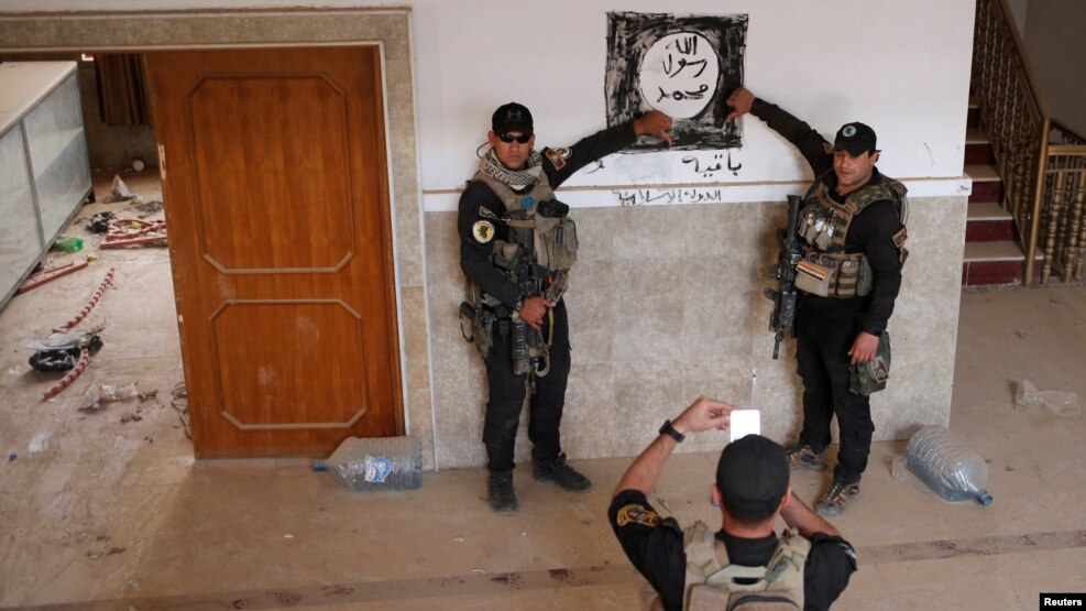 Iraqi special forces pose for a photograph in front of an Islamic States drawing inside a building east of Mosul on October 21.