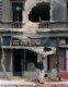 Two residents of Sarajevo walk past a destroyed building on Marshal Tito Avenue in June 1992