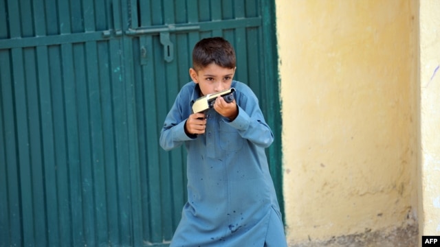 A boy holds a toy gun near the closed house of Rimsha, a Christian girl who has been arrested on blasphemy charges, in a slum area of Islamabad.