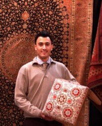 Hossein Ramezani shows a stool cover with an Uzbek design at the Domotex fair (RFE/RL)