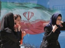 Iran --  Iranian women pass a billboard of Iran's national flag at a street in Tehran, 23Apr2007