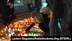 A woman in Kyiv adds a candle to an impromptu memorial for the victims of rocket attacks on Mariupol, which killed dozens of people on January 24.