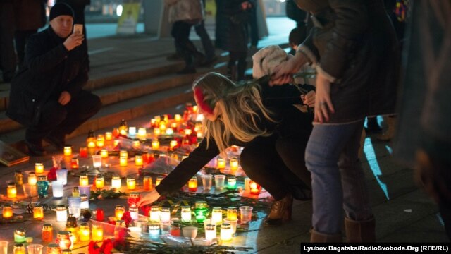 A woman in Kyiv adds a candle to an impromptu memorial for the victims of rocket attacks on Mariupol, which killed dozens of people on January 24.