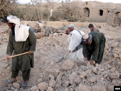 Men in the village in Farah Province search for their belongings after a U.S.-led air strike.