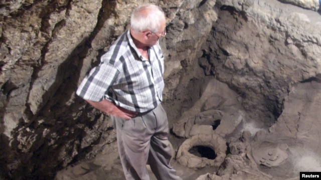 Armenia -- Archaeologist Levon Petrosian looks at a 6,100-year-old wine-making equipment discovered by an international project at the excavations of the Areni-1 cave complex, undated