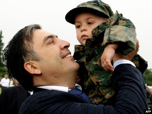 President Michael Saakashvili holds a child in a military uniform in Tbilisi in August, during a ceremony on the first anniversary of the war with Russia.