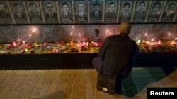 A man lights candles at a memorial dedicated to firefighters and workers who died after the Chornobyl nuclear disaster during a service near the Chornobyl plant in the city of Slavutych on April 26.