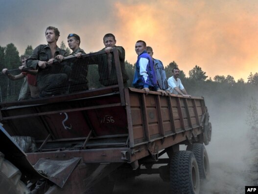 Volunteers ride on a trailer as they prepare to extinguish a fire at a forest near the village of Tokhushevo, some 50 kilometers outside Sarov.