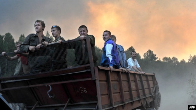 Volunteers ride on a trailer as they prepare to extinguish a fire at a forest near the village of Tokhushevo, some 50 kilometers outside Sarov.