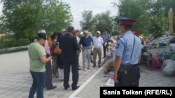 Саяси қуғын-сүргін және ашаршылық құрбандарын еске алуға жиналып тұрған бір топ белсенді мен оларды бақылап тұрған полиция қызметкері. Атырау, 31 мамыр 2016 жыл.