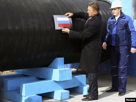 Gazprom Chief Executive Aleksei Miller attaches the Russian national flag to a pipe of the Nord Stream pipeline near the town of Vyborg in April. The pipeline should bring Russian gas directly to Germany, bypassing transit countries.