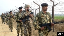 Indian Border Security Force soldiers patrol along the India-Pakistan border fence.