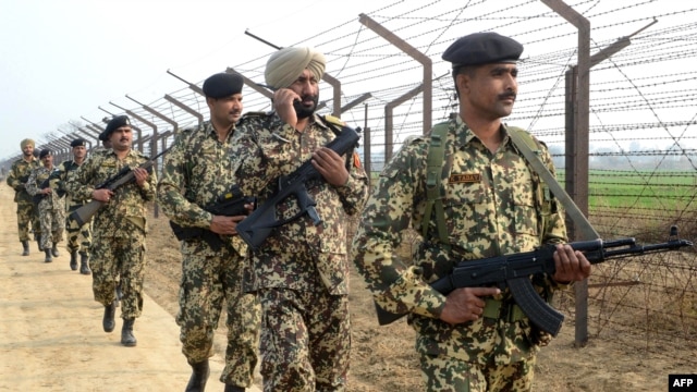 Indian Border Security Force soldiers patrol along the India-Pakistan border fence.