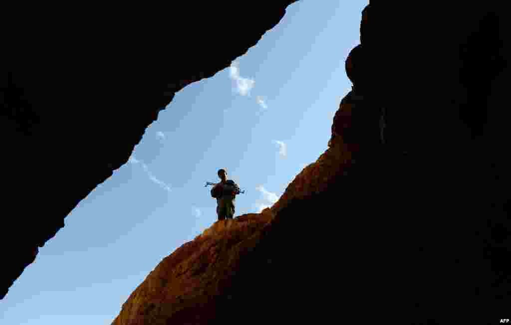 An Afghan policeman keeps watch over miners at work.