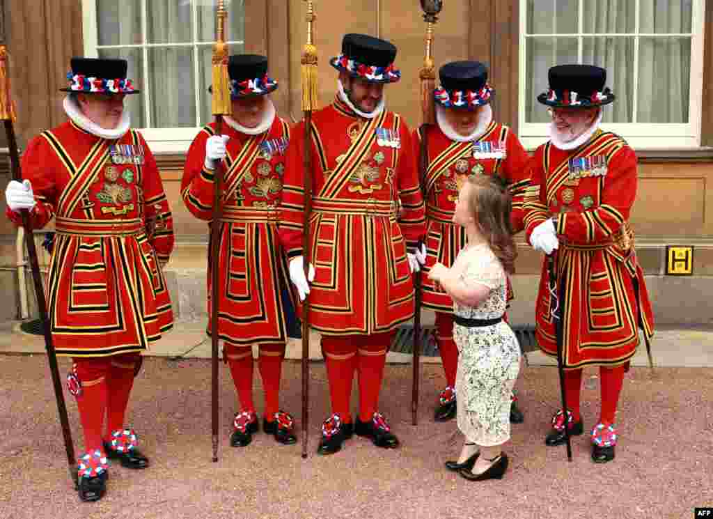 Britain's Paralympic swimmer Eleanor Simmonds poses with Yeomen of the Guard holding her medal after being appointed an Officer of the Order of the British Empire (OBE) by Prince Charles during an investiture ceremony at Buckingham Palace. Simmonds won four medals including two golds at the London 2012 Paralympic Games. (AFP/Sean Dempsey)