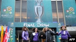 UEFA volunteers jump in front of the National Palace of Arts in Kyiv ahead of the December 2 draw.