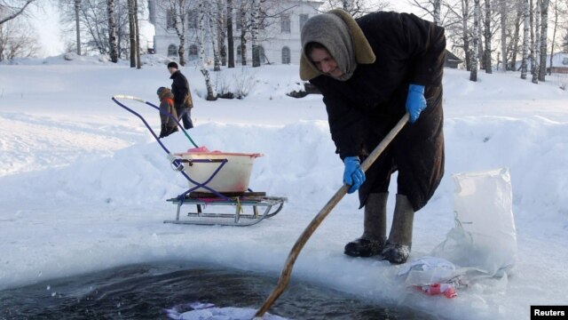 Старушка полощет белье в проруби на Сиверском озере в городке Кириллов
