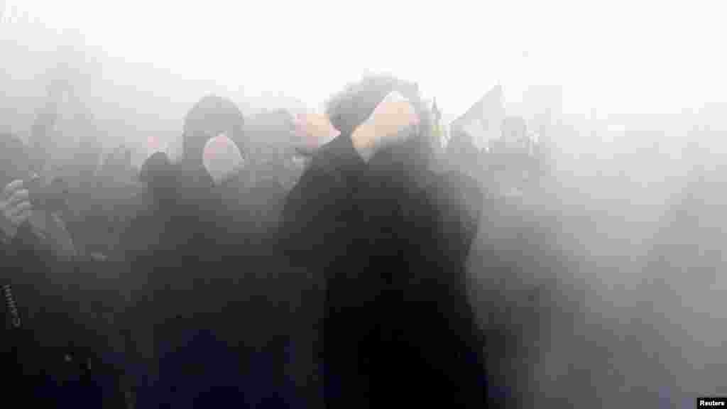 Nationalists cover their faces as they walk through smoke during the march.