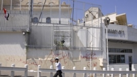 A policeman walks in front of the damaged U.S. embassy after pro-government protesters attacked the embassy and raised a Syrian flag on the compound in Damascus