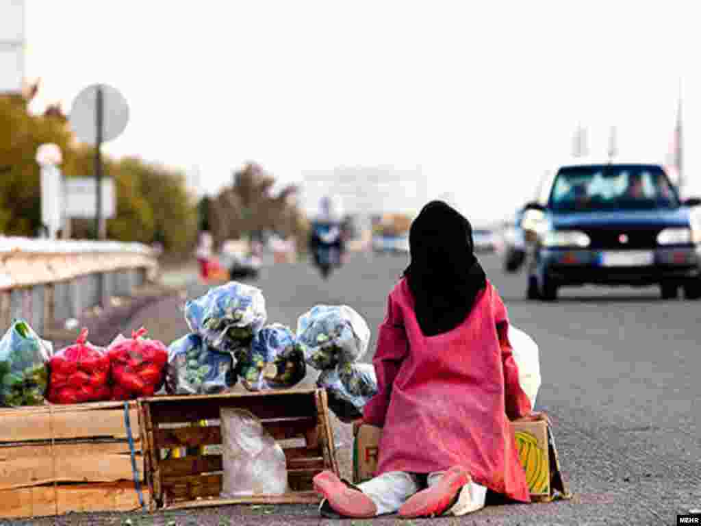 An Iranian girl sells vegetable to passing cars.