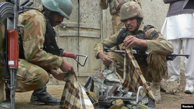 Security officials collect weapons near the site of a police station in Bannu after it was attacked by militants.