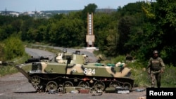 A Ukrainian soldier walks near a destroyed armored vehicle outside Slovyansk in eastern Ukraine on July 5.